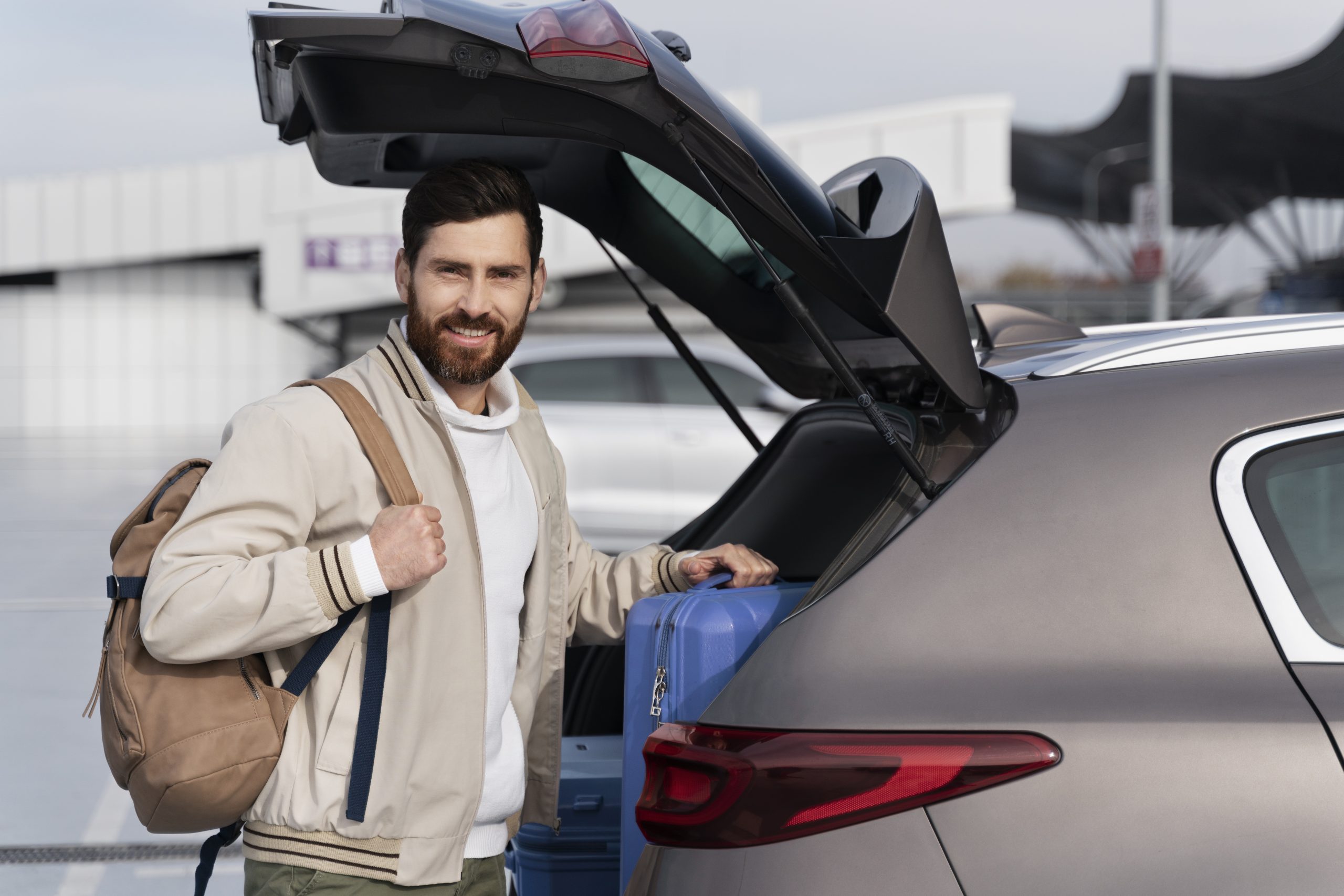 man putting luggage in british car transfer trunk